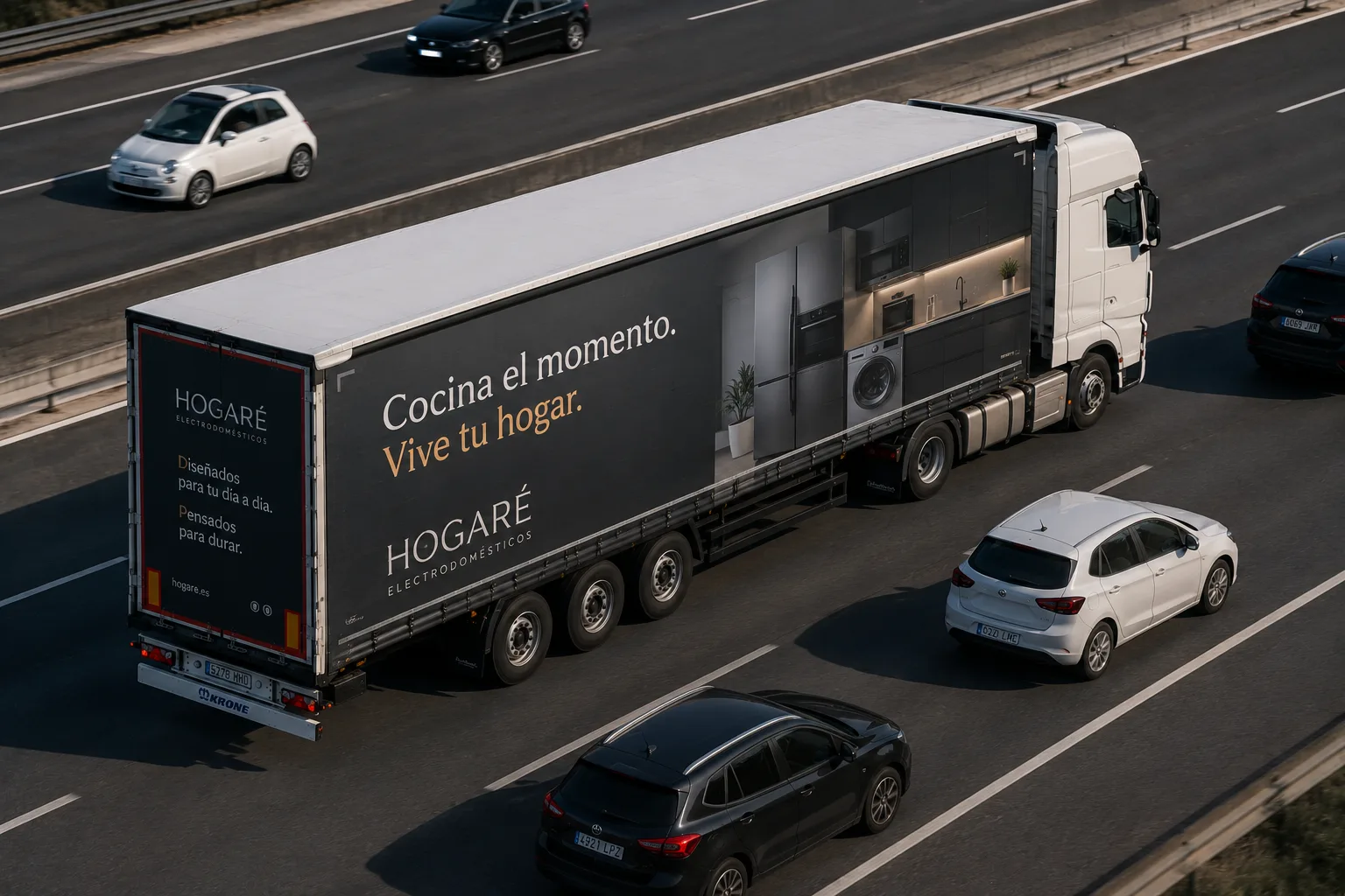 Tráiler con una campaña de electrodomésticos en todo el lateral, circulando por una autovía entre turismos